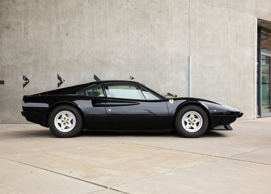 Black 1977 Ferrari 308 GTB dry sump  parked in front of a concrete wall.